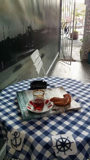 A table with a checkered tablecloth, a book titled 'mundo conceit', a glass of red drink, a baguette, and a small plate with a pastry. - Yacht House Istanbul (Istanbul)