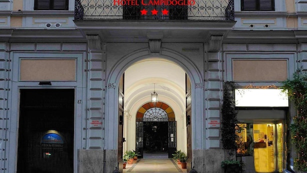 Hotel Campidoglion sisäänkäynti: punainen matto, kaareva oviaukko ja parveke, jossa on koristeellinen takorautakaide.