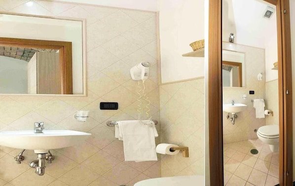 Un baño con lavamanos, espejo, toallero, inodoro y secador de pelo.