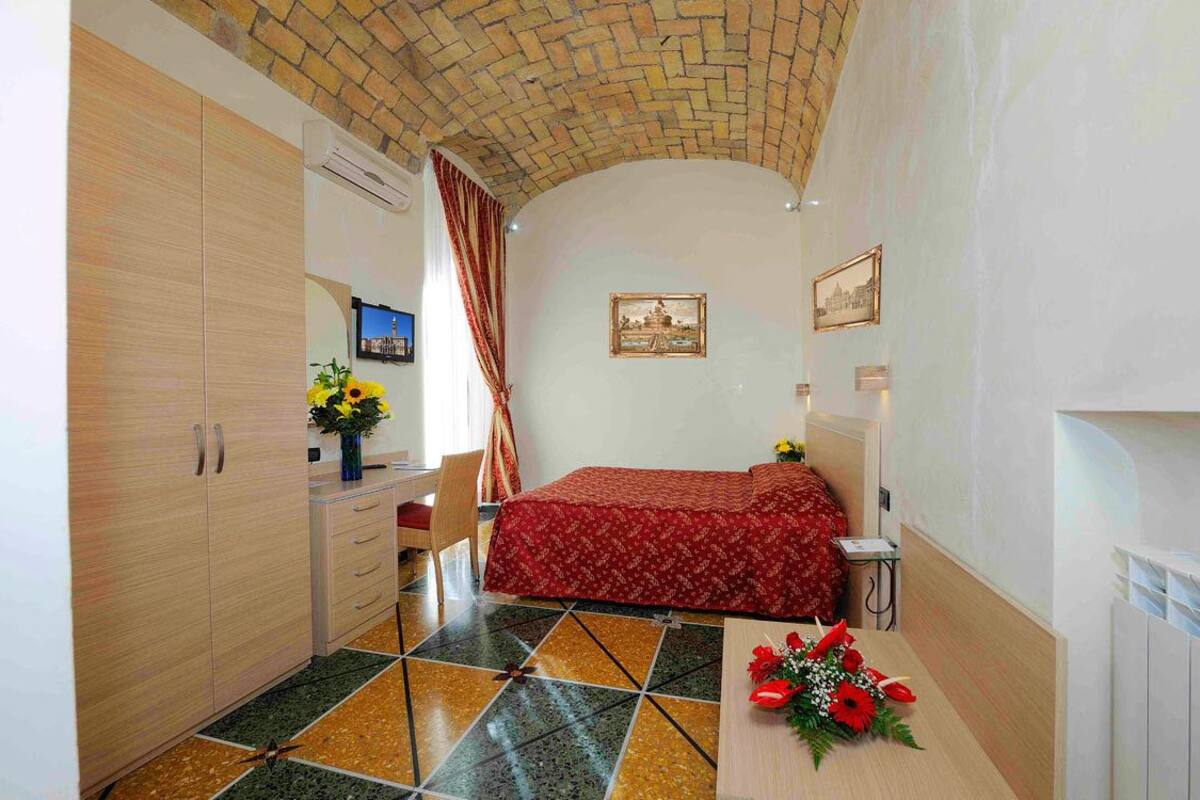 A bedroom with a bed, a desk, a chair, and a wardrobe.