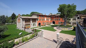 A courtyard with a stone building, a tree, and a paved walkway. - Residence Borgo Mondragon (Lazise)