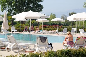 Una piscina al aire libre, sombrillas, tumbonas