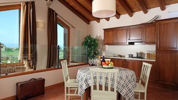Una cocina con armarios de madera, una mesa de comedor con mantel a cuadros y vistas por una ventana.