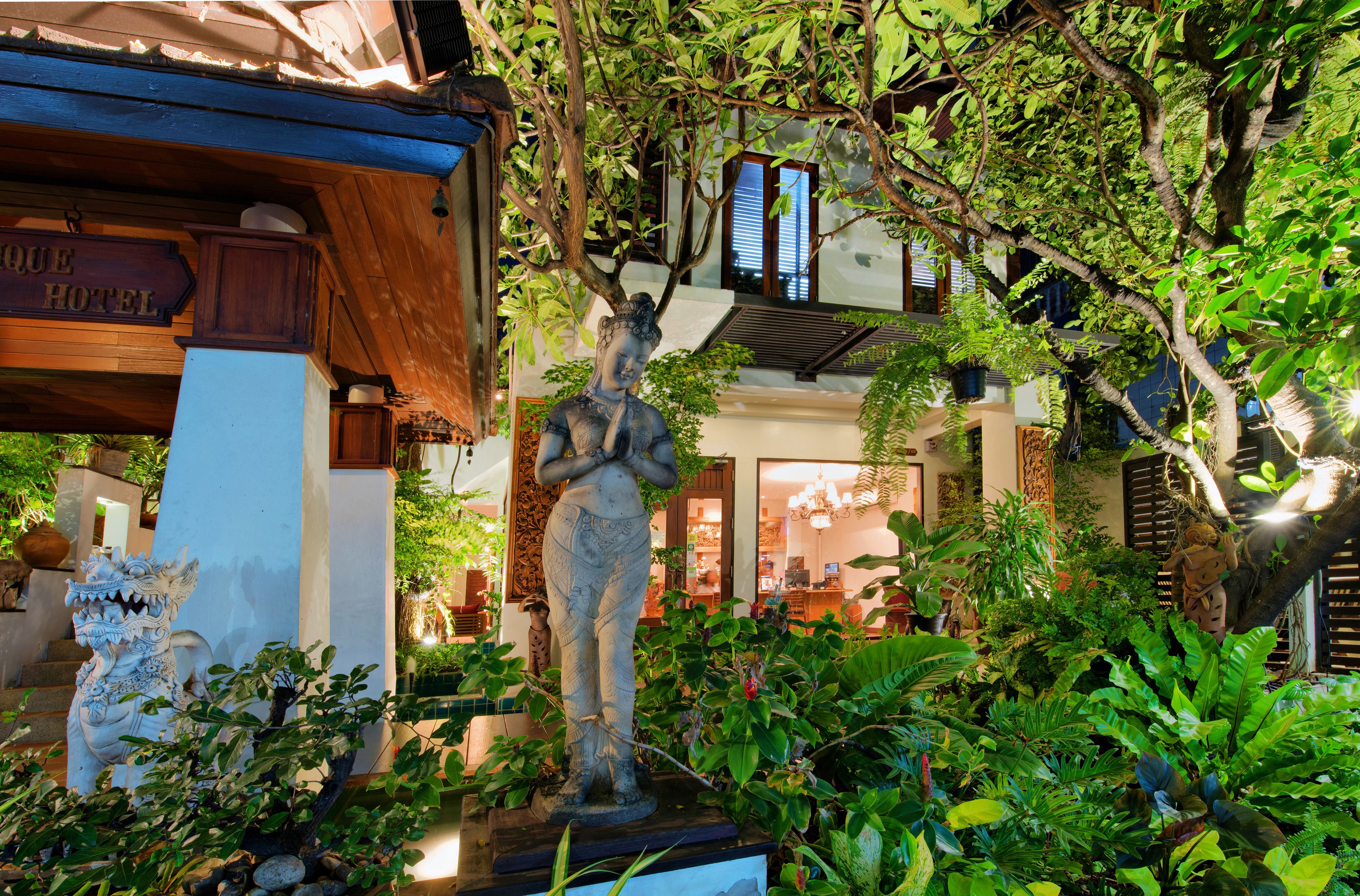 A statue in a lush garden setting with a sign for "Hotel".