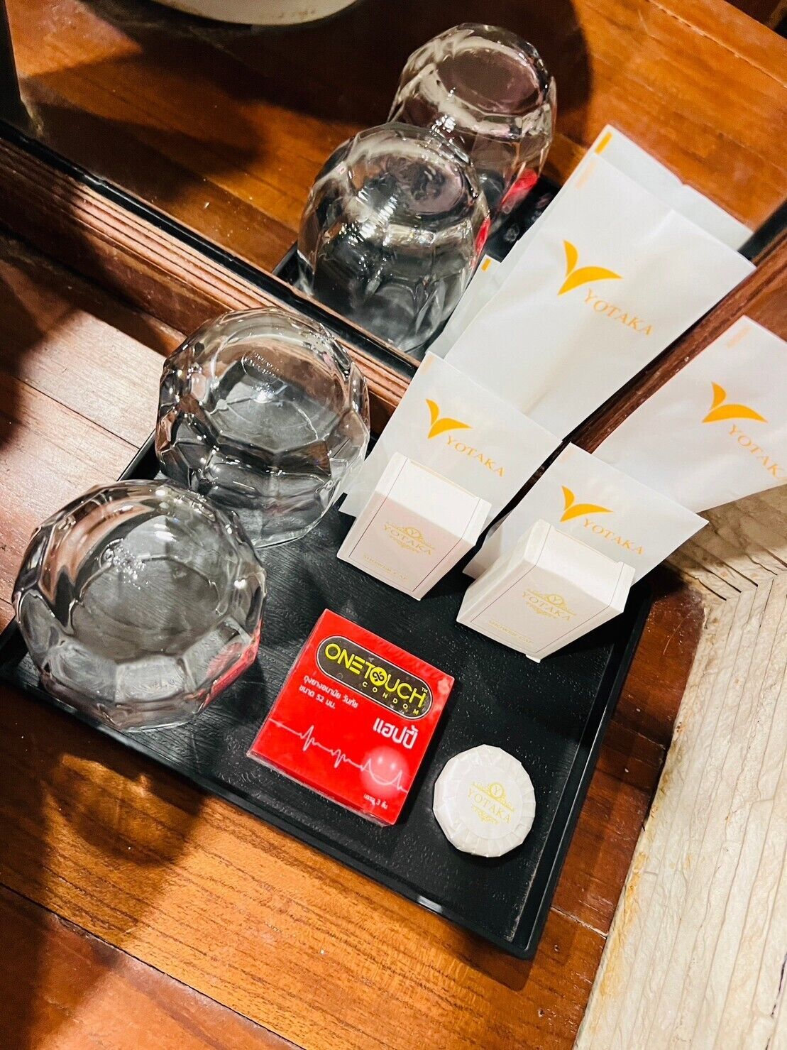 A tray with clear glasses, a red box labeled "ONETOUCH Lube," and white boxes with the "YOTAKA" logo.