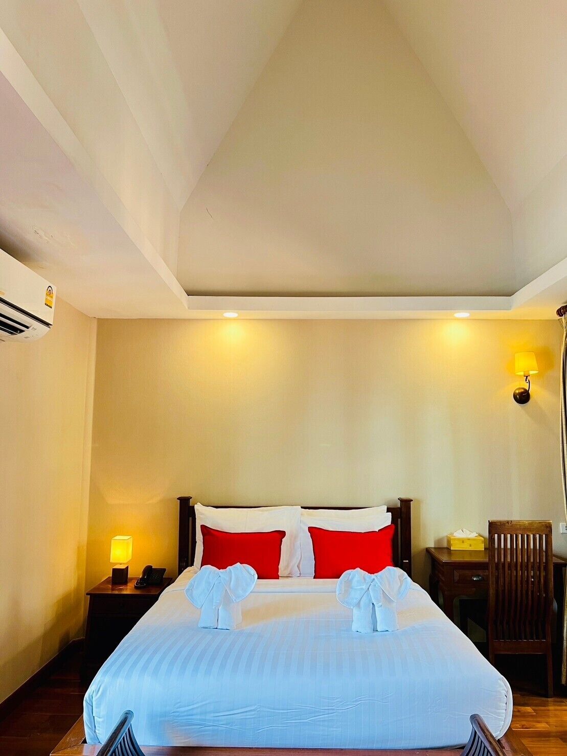 A hotel room with a bed, bedside tables, a lamp, and a chair.