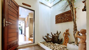 A wooden door leading to a room with a stone wall, a tree, and two terracotta statues. - Yotaka Boutique Hotel Bangkok (Bangkok)