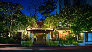 A traditional building with a covered entrance, steps leading up to it, and lush greenery surrounding the area. - Yotaka Boutique Hotel Bangkok (Bangkok)