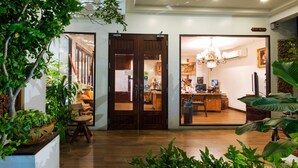 A spacious room with a wooden floor, a chandelier, and a desk with a computer. There are plants and a large window. - Yotaka Boutique Hotel Bangkok (Bangkok)