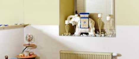 Una habitación de hotel con una cama, un reposacabezas azul, una mesita con una lámpara y un objeto decorativo en la pared.
