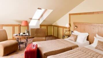 Ein Hotelzimmer mit zwei Betten, einem kleinen Tisch mit Lampe, einem Sessel und einem Koffer.