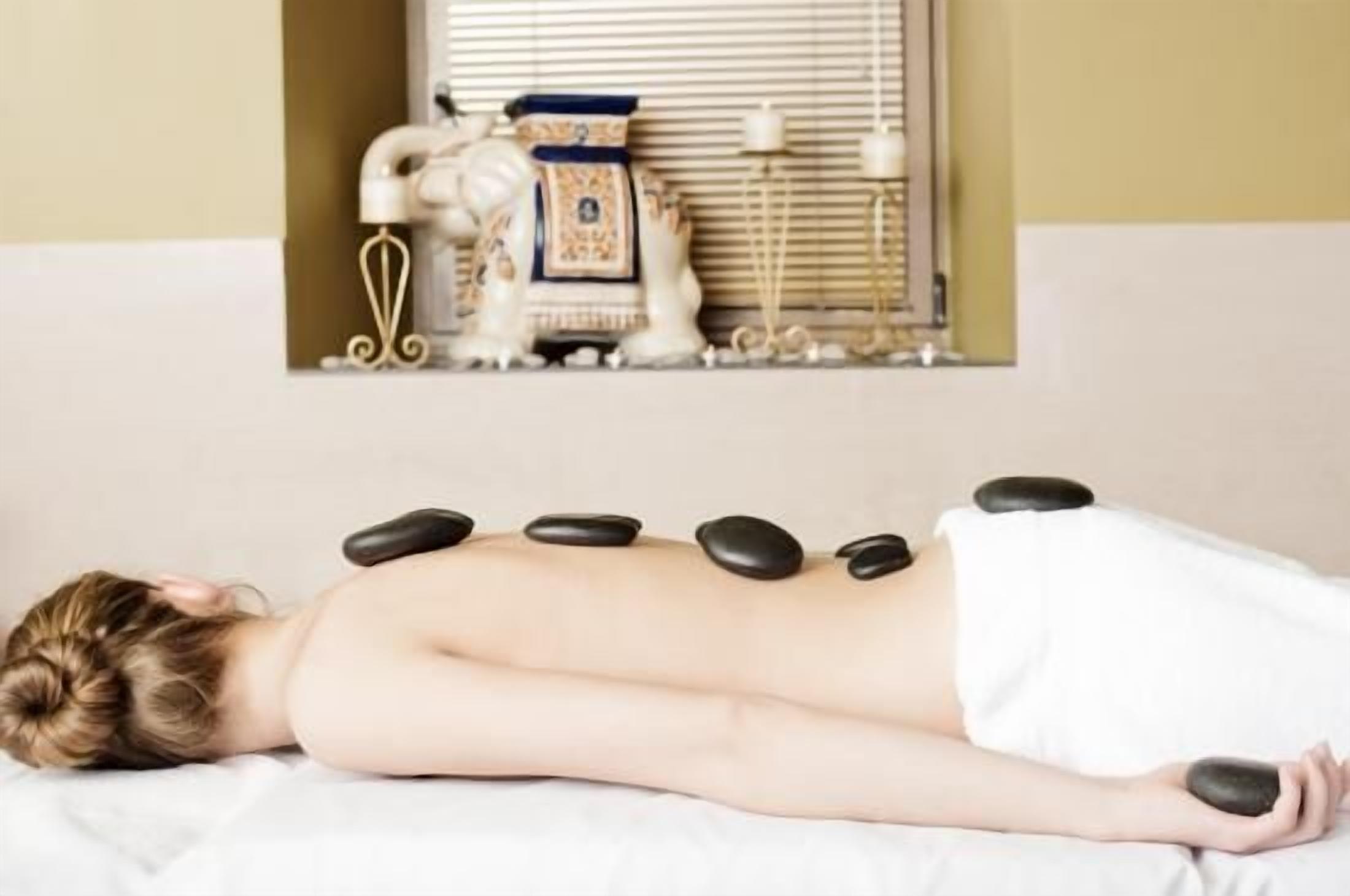 A person receiving a hot stone massage with stones placed on their back.