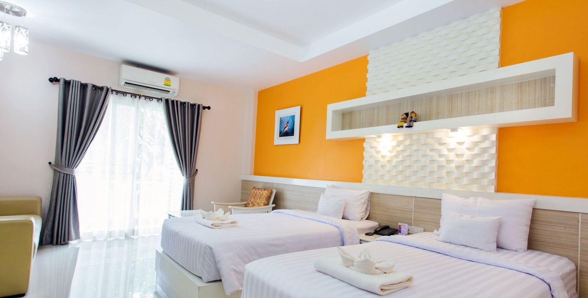 A hotel room with two beds, a desk, a chair, and a window with curtains.