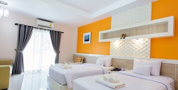 A hotel room with two beds, a desk, a chair, and a window with curtains.