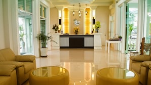 A reception area with a modern design, featuring a reception desk, potted plants, and a glass coffee table. - Nantrungjai Boutique Hotel (Nan)