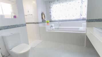 Un baño moderno con inodoro blanco, bañera y lavabo.