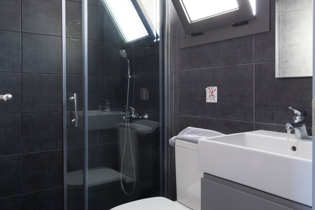 A modern bathroom with a glass shower enclosure, a white toilet, and a sink with a mirror above it.