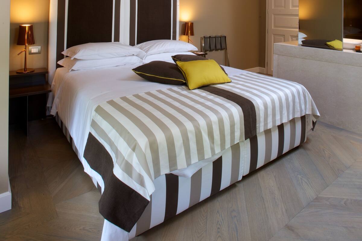 A bedroom with a large bed, wooden flooring, and a sloped ceiling.