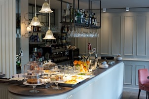 Angolo bar con diverse bevande, bicchieri e cibi esposti sul bancone.