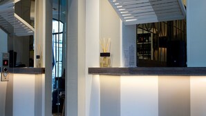 A modern hotel lobby with a glass elevator, a reception desk, and a large window. - Fuori Porta House (Bergamo)