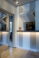 Una moderna hall d'albergo con un ascensore in vetro, una reception e una grande finestra.