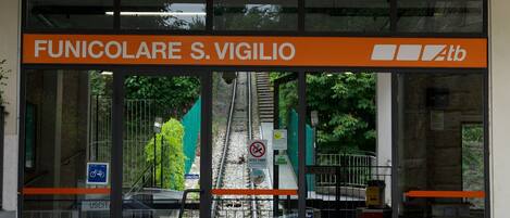 The entrance to Funicolare S. Vigilio, a funicular station with glass doors and a sign above.