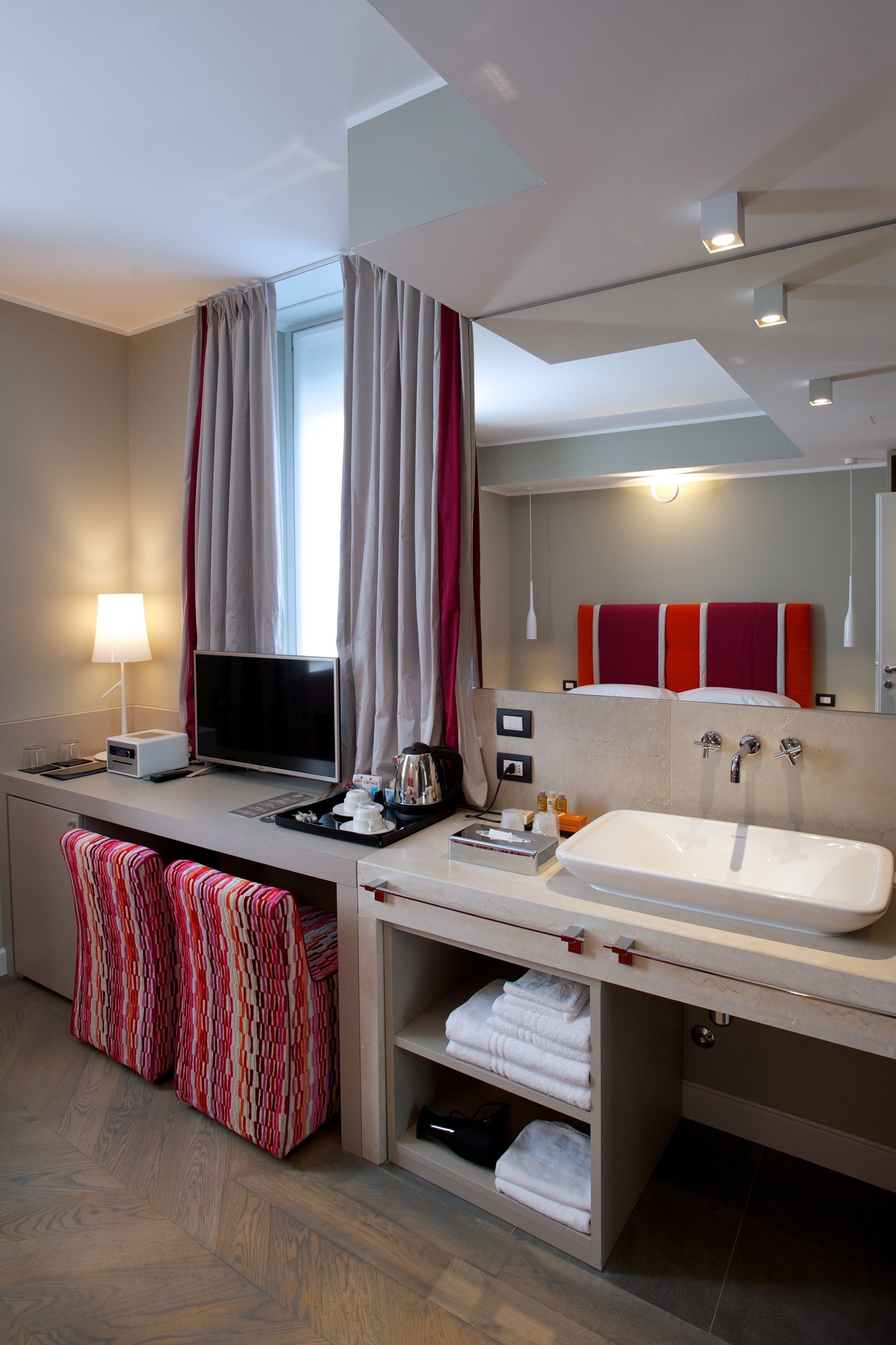 Une salle de bain d’hôtel moderne, dotée d’un grand lavabo, d’un miroir et d’une fenêtre avec des rideaux.