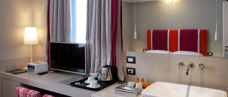 A modern hotel bathroom with a large sink, mirror, and a window with curtains.