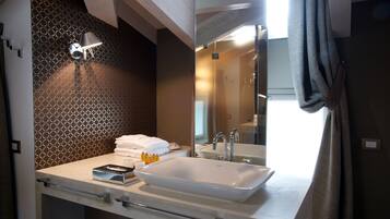 A bathroom with a large white sink, a mirror, a towel rack, and a patterned wall.