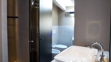 A modern bathroom with a large sink, a glass shower enclosure, and a skylight.