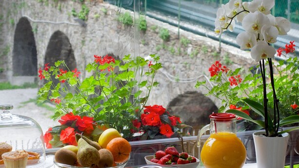 A breakfast buffet with various food items and a scenic view of a cable car in the background. - Fuori Porta House (Bergamo)