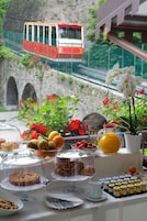 Un ricco buffet per la colazione con diversi cibi e vista panoramica su una funivia sullo sfondo.