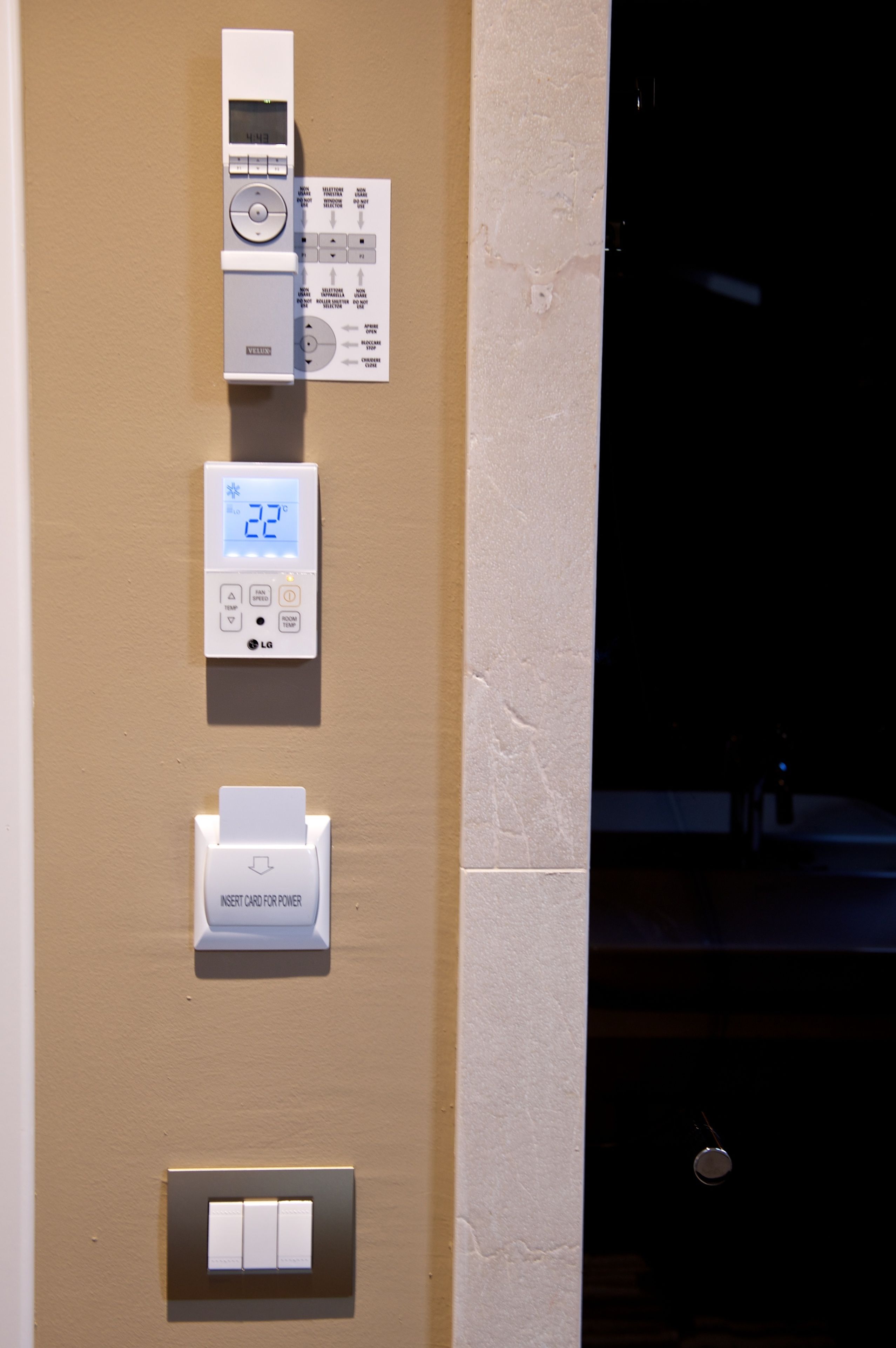 Un termostato fissato al muro dotato di display digitale, lettore di carte e interruttore.