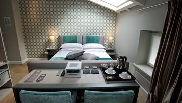 Habitación de hotel con cama, dos mesitas de noche con lámparas, escritorio con una bandeja de desayuno y ventana con cortinas.