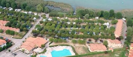 An aerial view of a residential area with houses, a swimming pool, and a body of water.