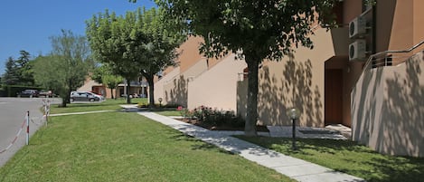 A residential area with a well-maintained lawn, a sidewalk, and a row of apartment buildings.