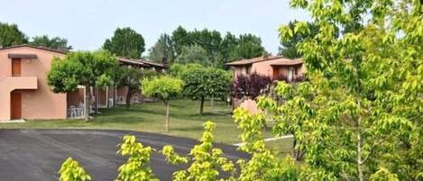 Un quartier résidentiel composé de deux immeubles, chacun doté d’un balcon et entouré de verdure.