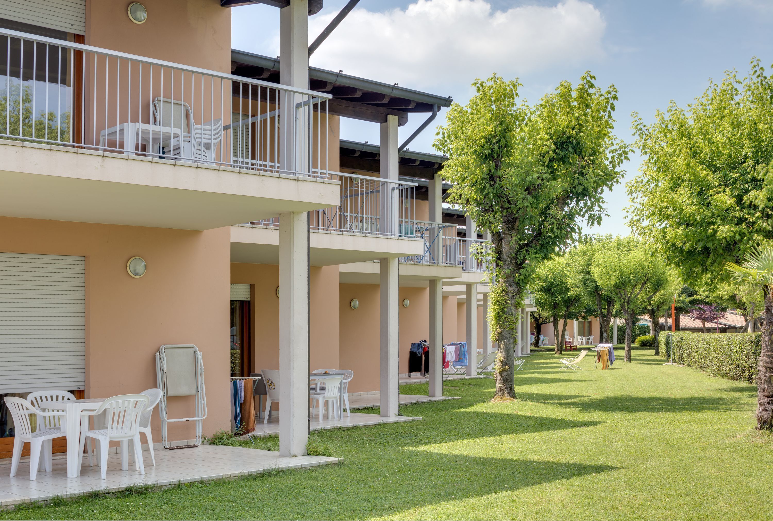 A multi-story building with outdoor seating, a covered patio, and a well-maintained lawn.