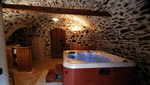 A stone-walled room with a wooden bench, a wooden cabinet, and a hot tub. - Appartamenti Pellizzano (Pellizzano)