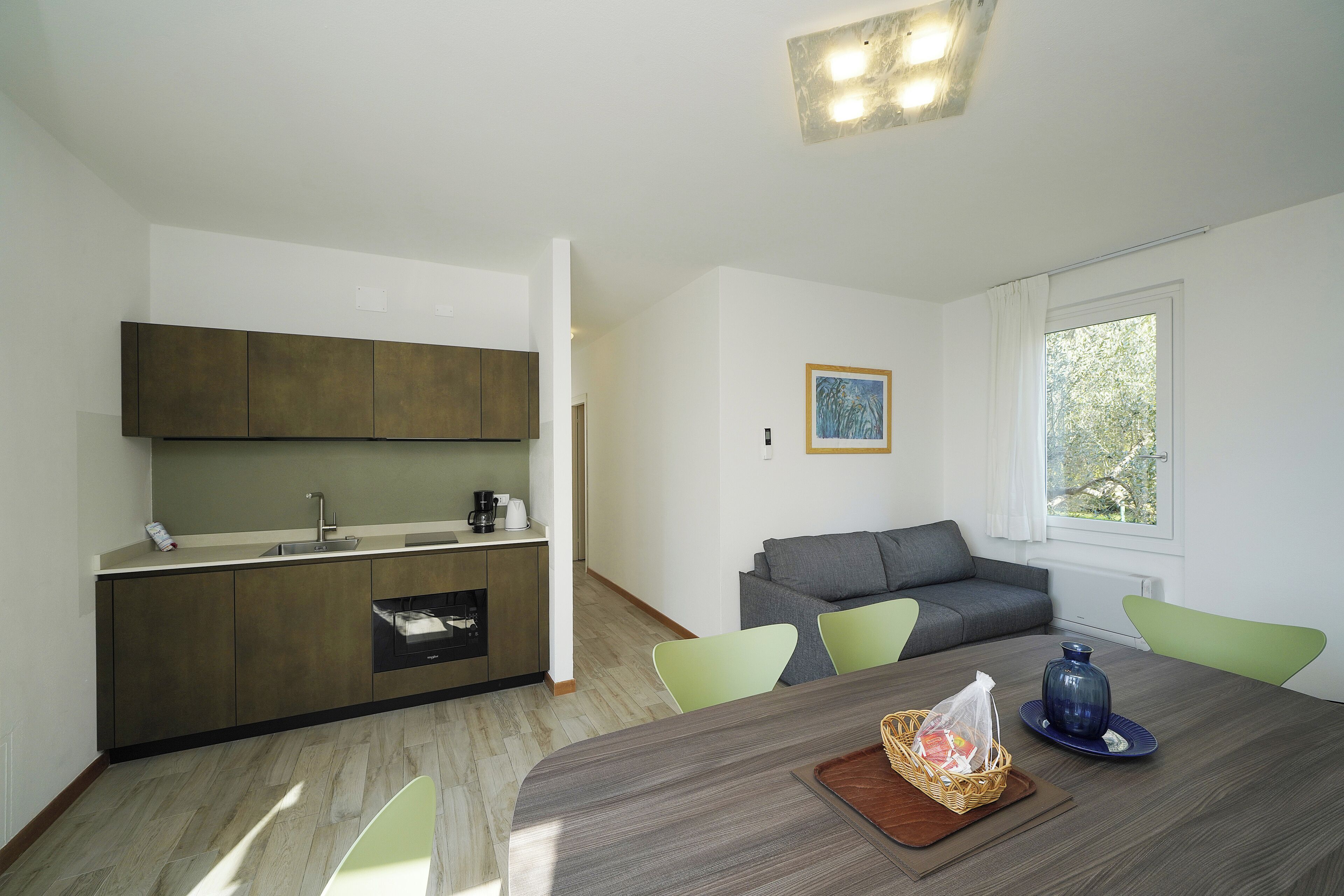 A modern kitchen with a dining area, a sofa, and a window with a view.