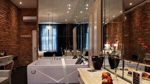 A modern bathroom with a large bathtub, a vanity with a mirror, and a window with curtains. - Betmanowska Main Square Residence Adults Only  (Kraków)