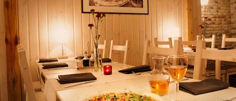Una mesa de comedor con pizza, copas de vino y una vela.