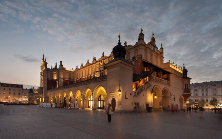 A historic building with arched windows and a central dome, featuring a spacious plaza in front.