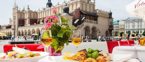 A dining table with a meal, wine glasses, and a flower arrangement at Virtuoso Restaurante.