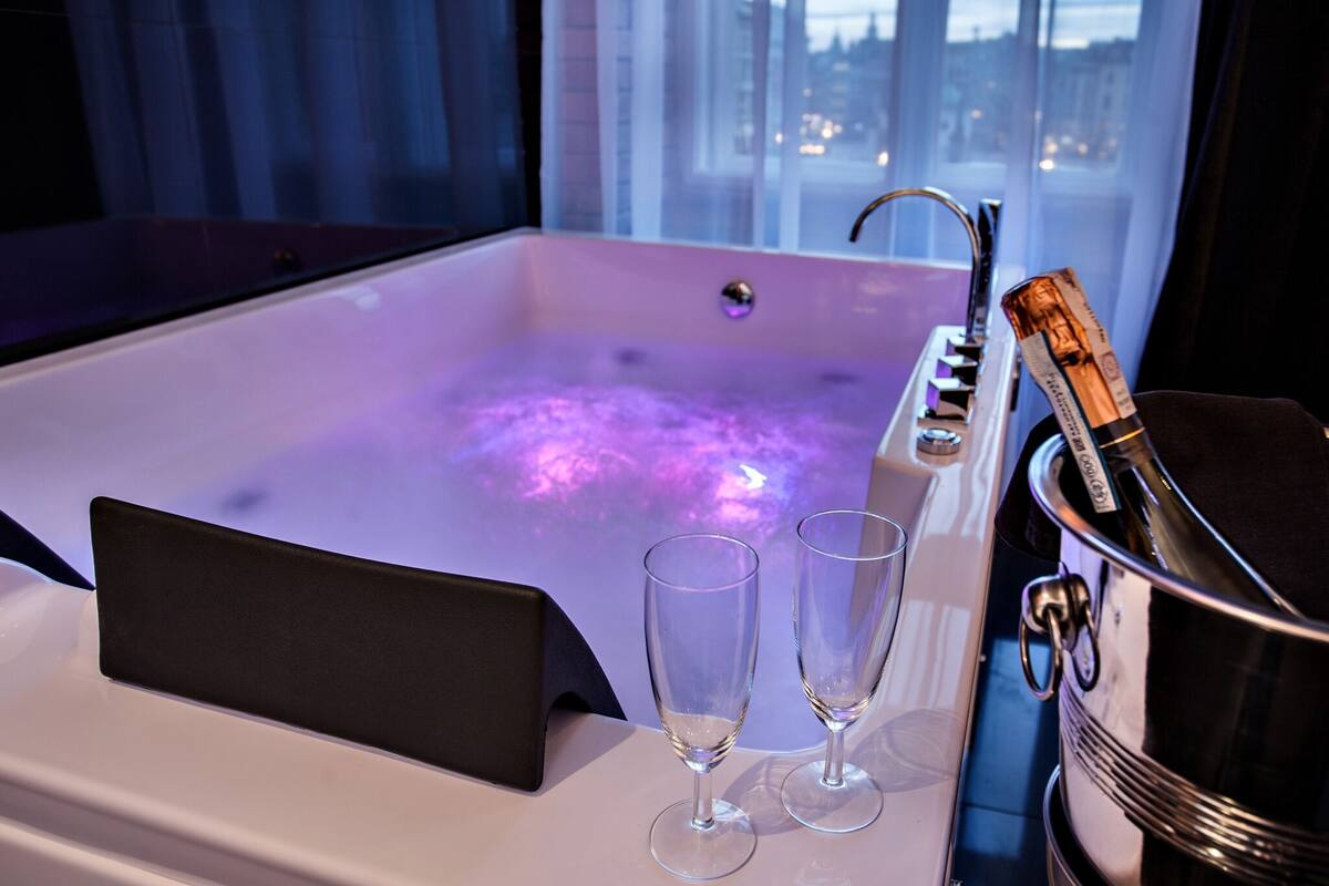 Ein Whirlpool mit Blick auf die Stadt, zwei Gläser und eine Champagnerflasche.