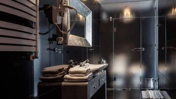 A modern bathroom with a large mirror, a towel rack, and a shower area.