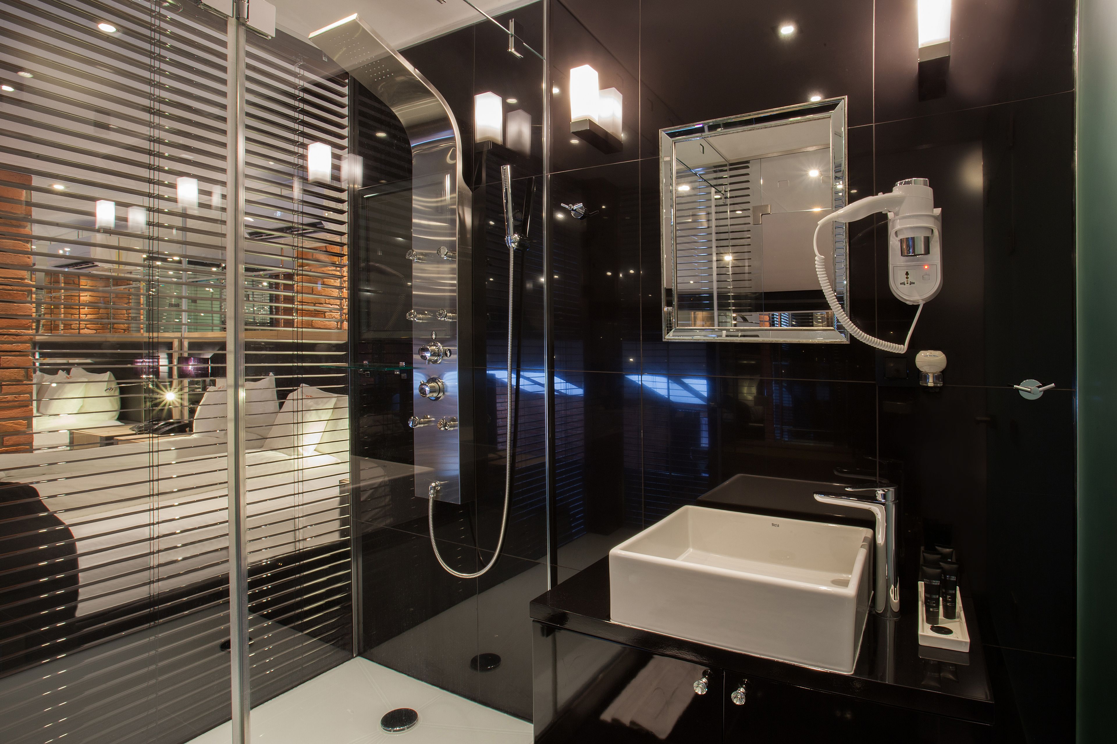 A modern bathroom with a glass-enclosed shower, a white sink, and a mirror above it.