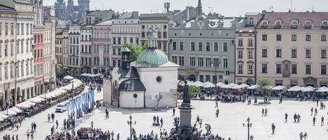 Una plaza pública con un monumento central, rodeada de edificios históricos y cafés.