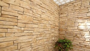 A room with a stone wall and a wooden floor, a potted plant, and a skylight. - Residence Corte Leonardo (Garda)