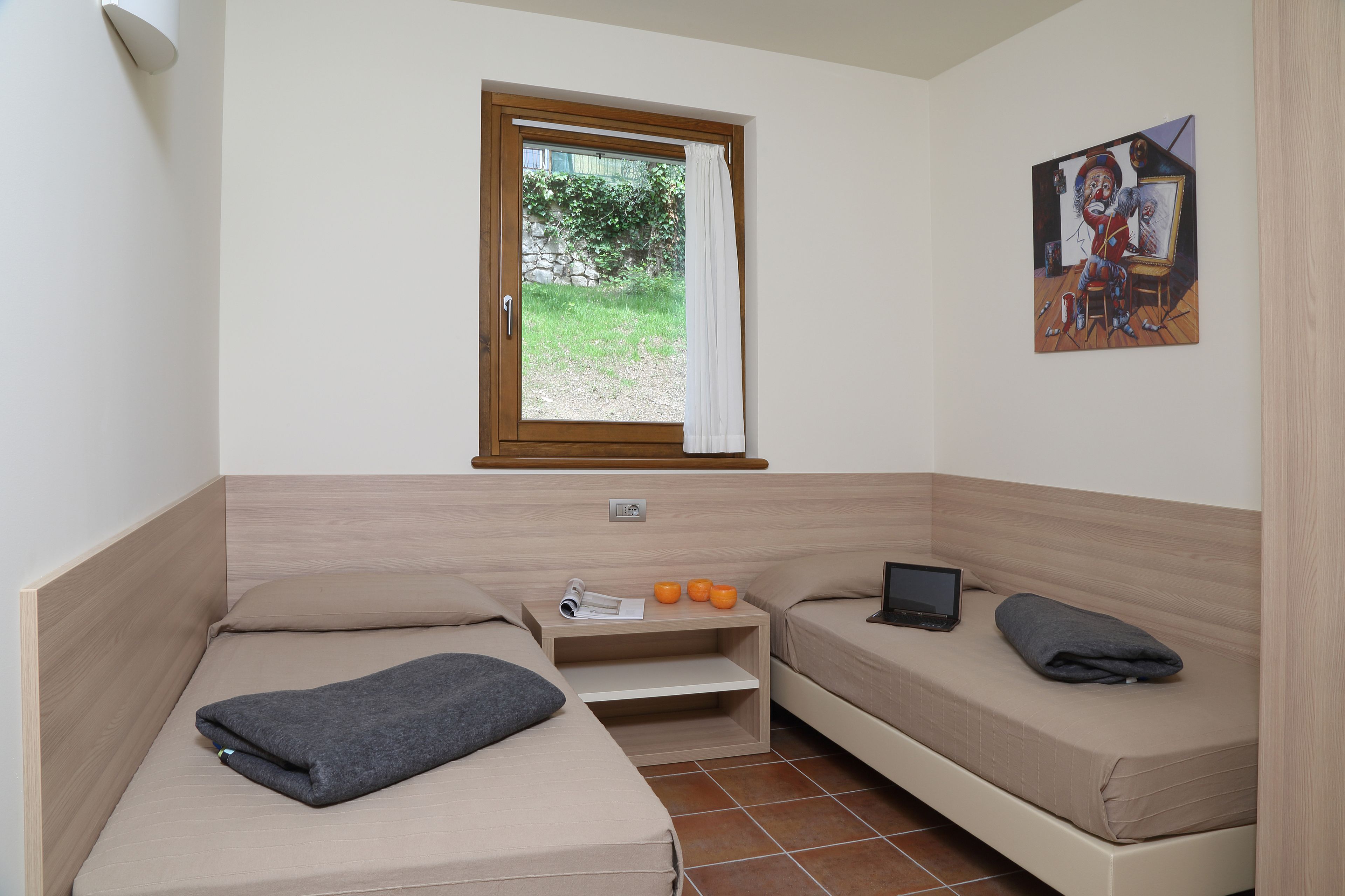 A small, modern room with a bed, a desk, and a window.